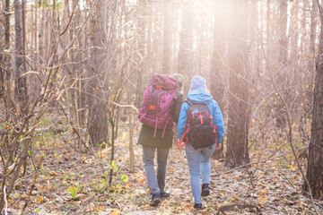 Travel, tourism, hike and people concept - Couple with backpacks walking in the autumn forest, back view