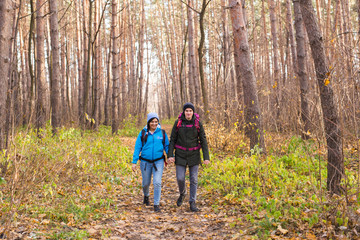 Obraz premium Travel, tourism, hike and people concept - Couple with backpacks walking in the autumn forest