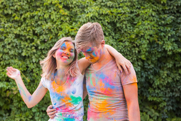 Friendship, festival of holi, people concept - young couple playing with colors at the festival of holi