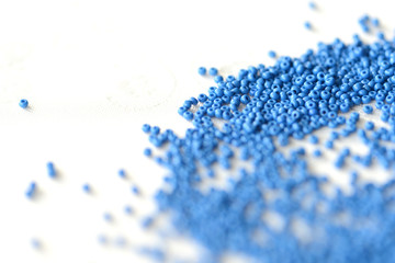 Seed beads dark blue color scattered on a textile background close up