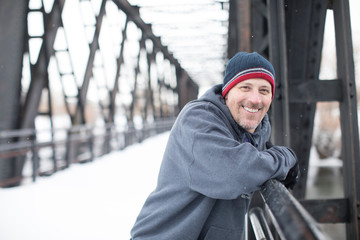 Handsome middle-aged athlete on bridge in winter