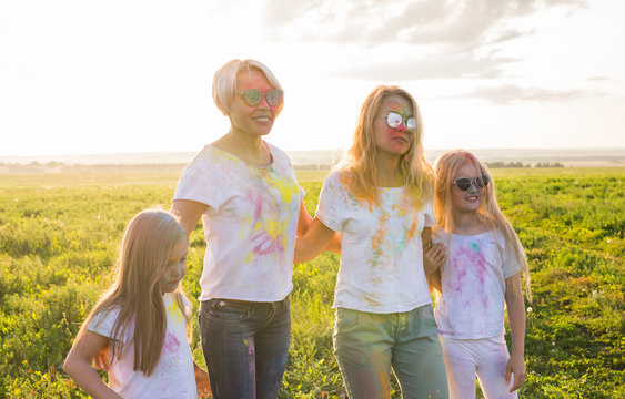 Festival of holi, friendship, happiness and holidays concept - little girls and women in glasses hugging on the festival of Holi.