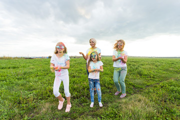 Fototapeta premium Holi festival, holidays and happiness concept - young teens and women in colors have fun outdoor