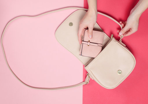 Female Hand Takes A Leather Wallet From A Bag On A Pastel Background. Top View, Flat Lay, Minimalism