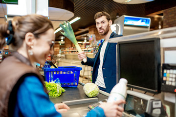 Handsome businessman putting products on the cash register buying food in the supermarket