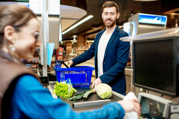 Handsome businessman putting products on the cash register buying food in the supermarket
