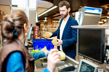 Handsome businessman putting products on the cash register buying food in the supermarket