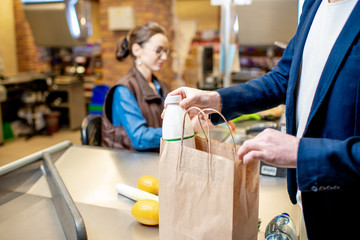 Businessman buying healthy food, packing products at the cash register with cashier on the...