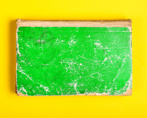 Old book with green shabby cover on a yellow background