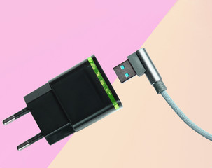 Adapter for charging smartphone, usb cable on pastel colored background