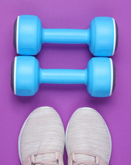 Sport shoes with dumbbells on purple background, top view, flat lay