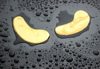 Patches under the eyes on a dark background in drops of water