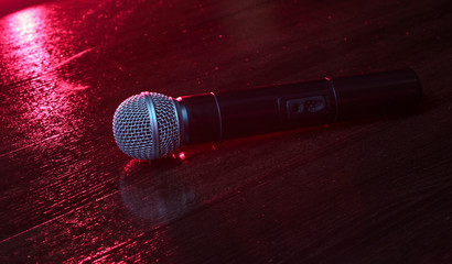 Karaoke. Nightlife concept. Microphones close-up on a wooden table. Dark red neon light