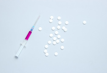 Medical concept, injection, vaccination. Syringe with purple liquid, pills on  gray background. Copy space