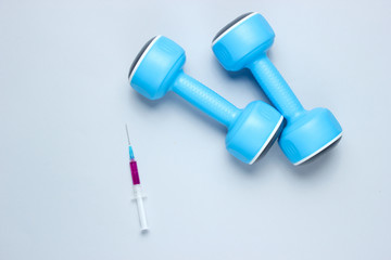 Doping in sport. Anabolic steroid. Sports Pharmacy. Blue plastic dumbbells, syringe on gray...
