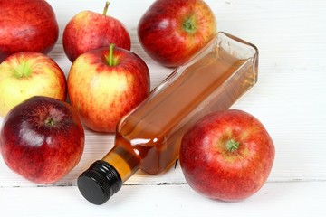 Apple vinegar and apples. Fresh apples, apple vinegar, measuring tape and a bottle  on white wooden table