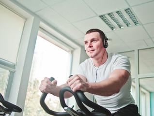 Healthy lifestyle concept. Young sporty man in white t-shirt and shorts is exercising bike at...