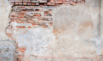 Old grungy red brick wall with peeled beige stucco background. Vintage retro plaster wall with...