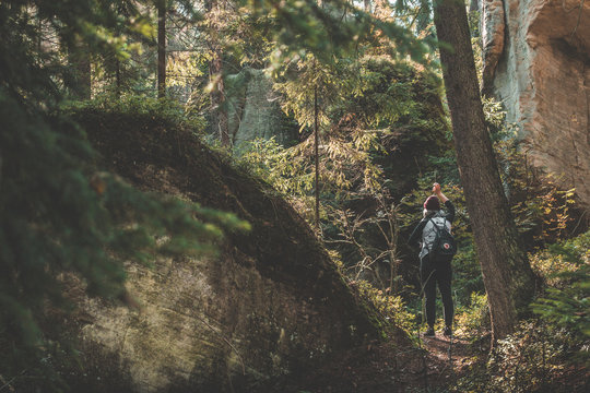 Woman with Fj&auml;llr&auml;ven Kanken backpack standing next to rock in autumn forest