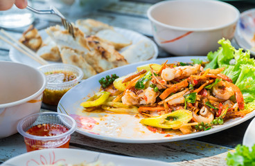 Close up view. Stir fried seafood in a plate placed on wooden table of restaurants by the sea.