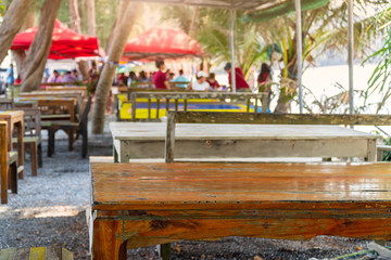 Fototapeta na wymiar Empty wooden tables of beach restaurants. Blurred view a lot of people come to eat seafood. Along with taking the family to visit.