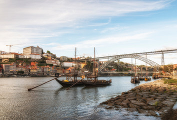Ancient sailing vessels on Douro River. Dom Luis Bridge. Porto, Portugal.
