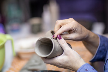 Fototapeta na wymiar Hands of artist who make a mug from ceramic clay in studio