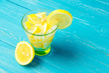 Water with lemon. Lemonade with lemon slices on blue wooden background.