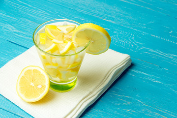 Water with lemon. Lemonade with lemon slices on blue wooden background.