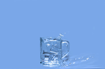 Water splashing out of a glass against a blue background. Pure water concept.