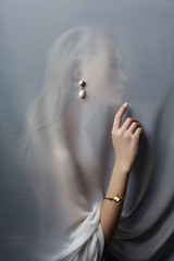 Earrings and jewelry in the ear of a sexy woman inserted through a transparent fabric. Perfect...
