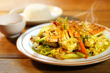 Top view of Fried crab with curry powder, popular seafood menu in asia. Fried crab with curry powder, onion and egg on wooden background. Selective focus, shoot in studio. Clean food concept.