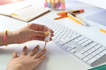 Cropped shot woman painting nails on office desk.