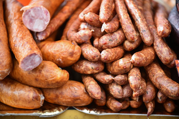 Delicious pieces of smoked sausage exposed for sale in the market. Selective focus and small depth of field
