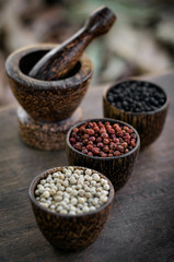 Organic white red and black pepper corns in wood display