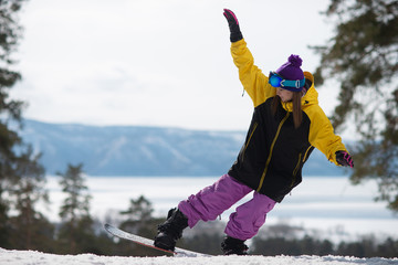 Woman riding a snowboard jumps. Winter sports. Girl in gear on a snowboard