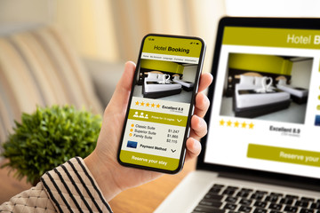 female hand holding phone with app hotel booking on screen