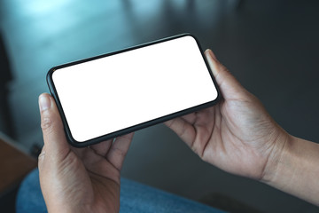Mockup image of a woman's hand holding black mobile phone with blank desktop screen horizontally