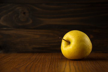 Yellow apple on the wooden vintage background