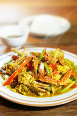 Top view of Fried crab with curry powder, popular seafood menu in asia. Fried crab with curry powder, onion and egg on wooden background. Selective focus, shoot in studio. Clean food concept.