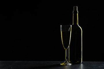 Bottles of wine and different glasses of wine on a dark background