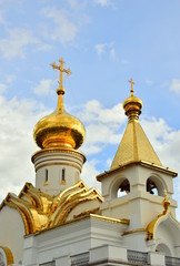 Fototapeta na wymiar The dome of the orthodox church. White walls of the temple, beautiful gilded Kupala, blue sky. Close up.
