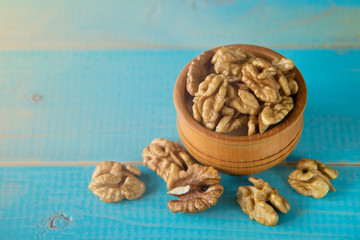 Walnuts on blue rustic table in wooden bowl