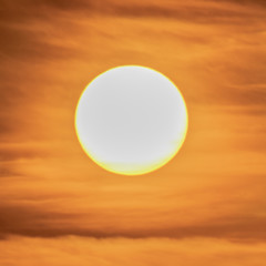 Extreme close up of the sun setting with dramatic red clouds at sunset. Squared image. High Definition - Shot with pro zoom lens