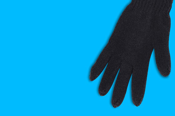 Black warm woolen glove on blue background with copy space for your text. Top view
