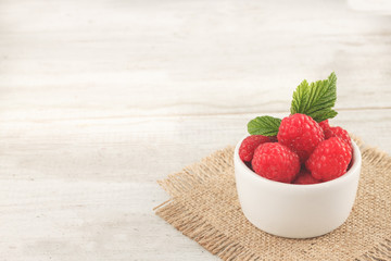 Raspberry in bowl. Raspberry on blue bacground with copy space for text.