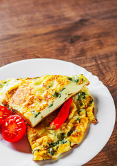 omelet with spinach in white plate on wooden table background