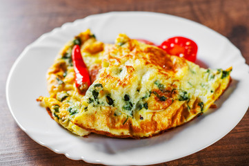 omelet with spinach in white plate on wooden table background