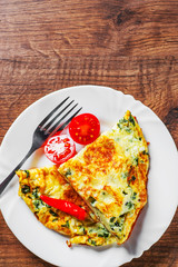 omelet with spinach in white plate on wooden table background