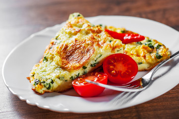 omelet with spinach in white plate on wooden table background
